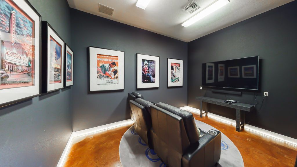 A cozy home theater setup with leather seating and movie posters on the walls.