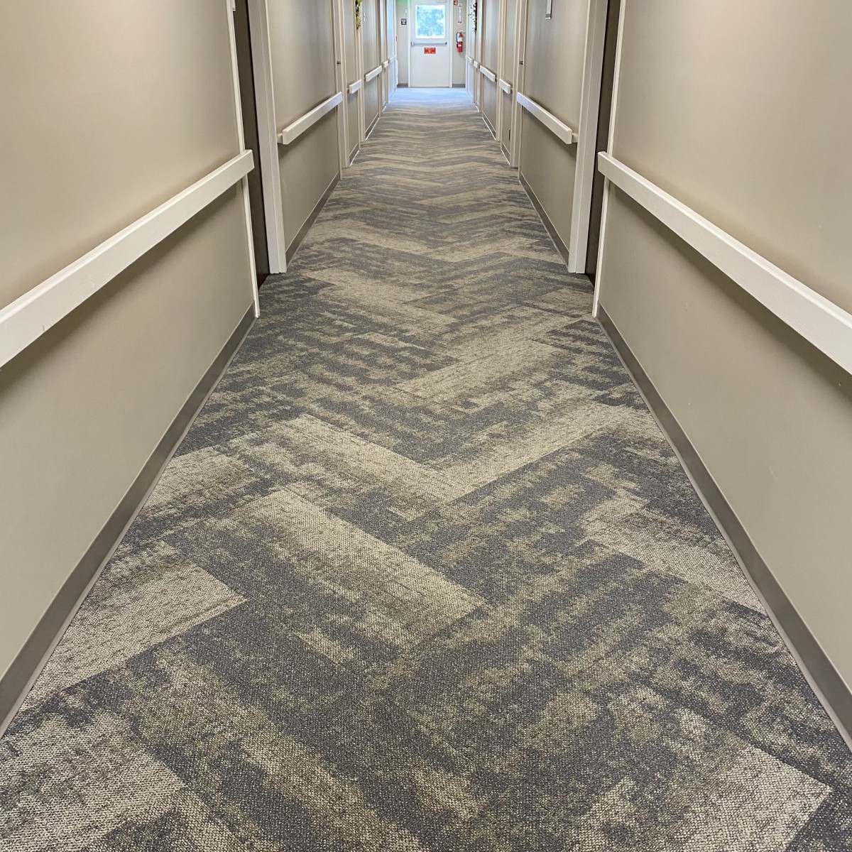 A long, carpeted hallway with patterned flooring and neutral-colored walls.