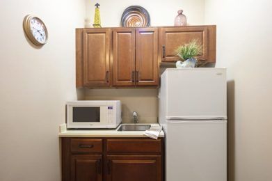 Compact kitchen area with a microwave, refrigerator, and cabinets.
