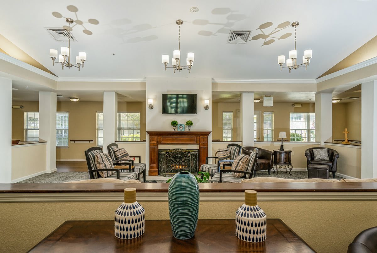 A spacious living room with a fireplace, chandeliers, and decorative vases.