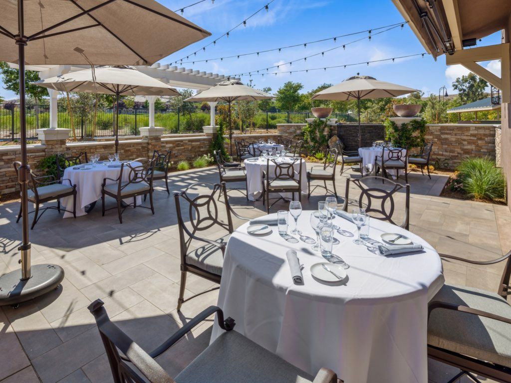 An outdoor restaurant patio with neatly set tables under large umbrellas, perfect for daytime dining.