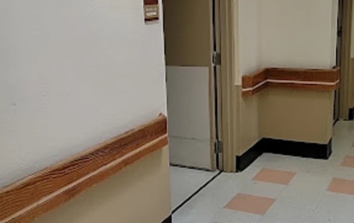 A view of a hospital hallway with an open door revealing part of the interior.