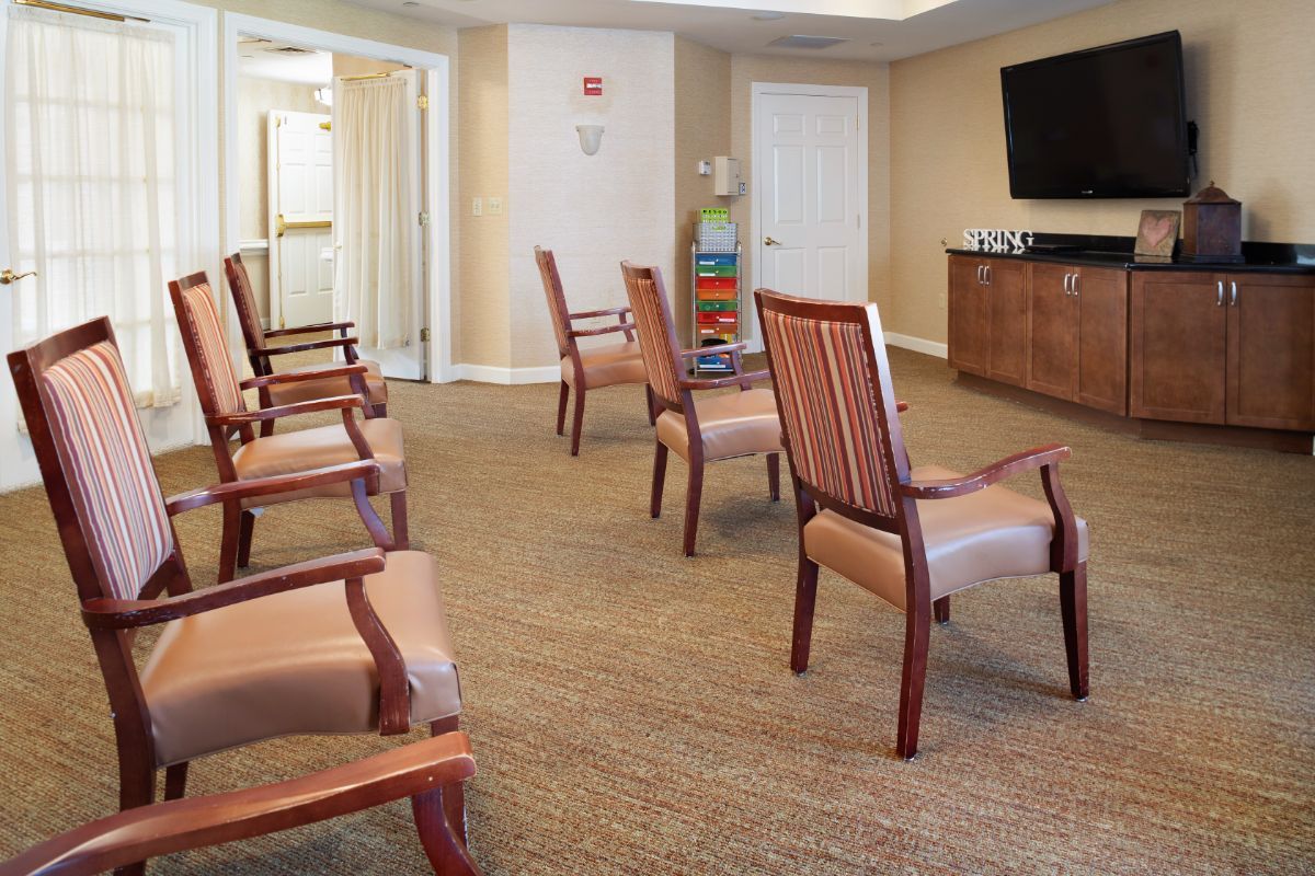 An empty waiting room with chairs arranged in a circle around a television.