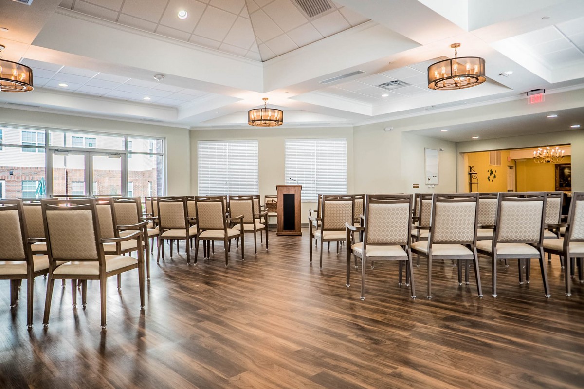 An empty meeting room with arranged chairs and wooden flooring.