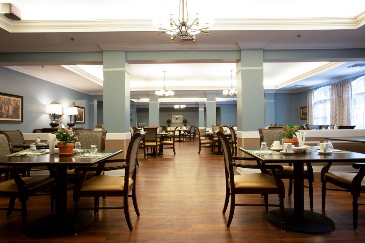 A spacious dining room with elegant chandeliers, neatly arranged tables, and a warm ambiance.