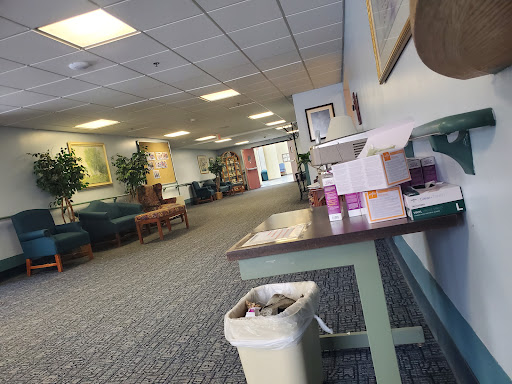 A spacious waiting area with comfortable seating, plants, and a table.