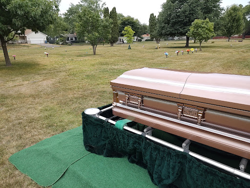 A coffin set up for a funeral service in a serene cemetery.