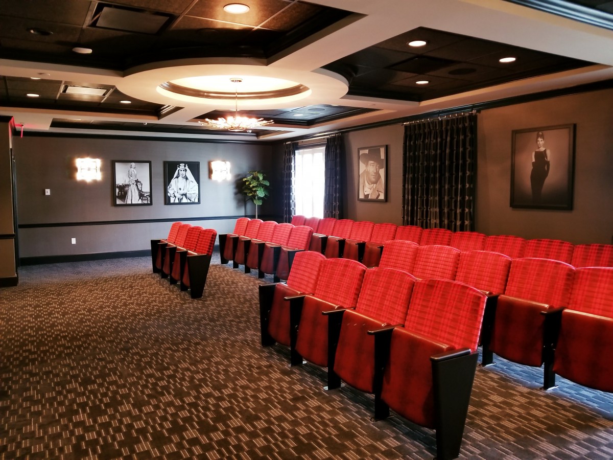 Luxurious theater with rows of red seating and elegant decor.