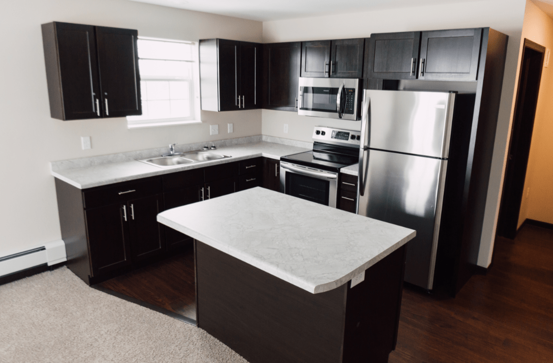 A modern kitchen with dark cabinets, a central island, and stainless steel appliances.