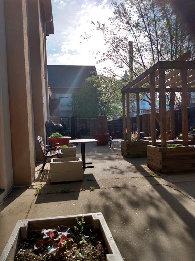 A serene outdoor courtyard basking in sunlight, featuring seating areas and greenery.