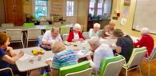 A group of seniors engaged in a crafting activity around a table.
