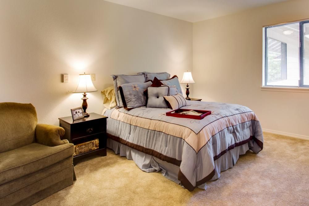 A cozy, well-decorated bedroom featuring a neatly made bed with pillows and two bedside lamps.