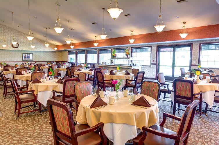A spacious and elegantly decorated restaurant dining room with neatly arranged tables and chairs.
