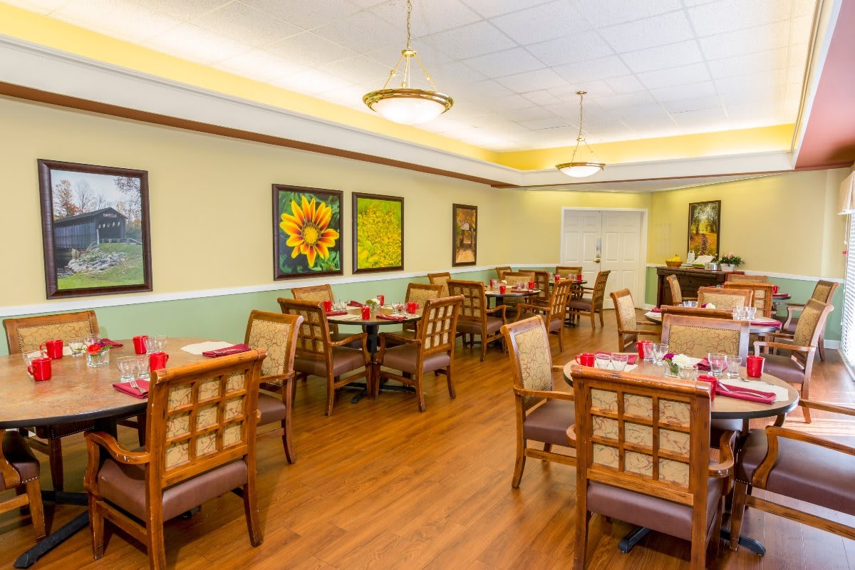 A cozy indoor dining area with tables and chairs arranged neatly, featuring colorful artwork on the walls.