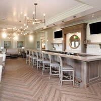 A modern bar interior with elegant chandeliers and wooden flooring.