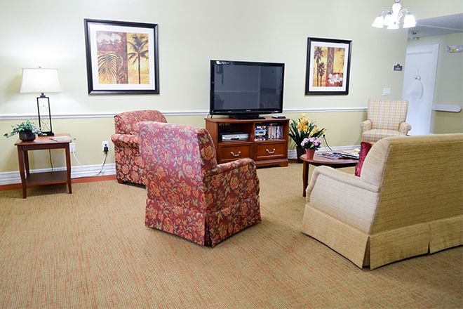A cozy living room with a television, armchairs, and decorative artwork.