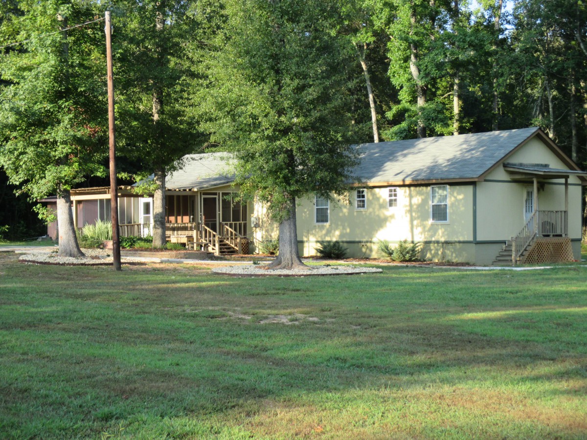 A small house with a surrounding yard and trees in a peaceful outdoor setting.