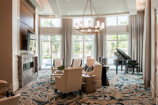 A beautifully designed lounge area featuring comfortable seating, a grand piano, and ample natural light.