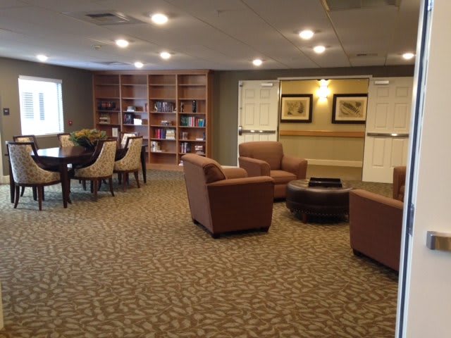 A cozy lounge area featuring comfortable chairs, a round table, and a bookshelf.