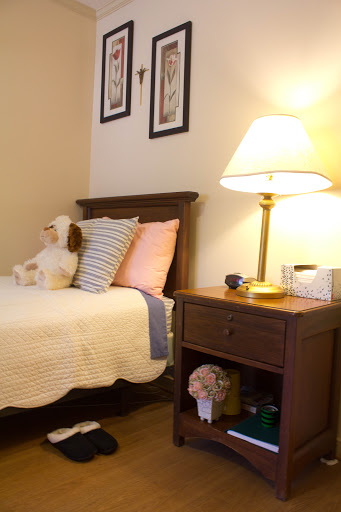 A cozy bedroom setup featuring a neatly made bed with pillows, a lamp on the nightstand, and charming decor.