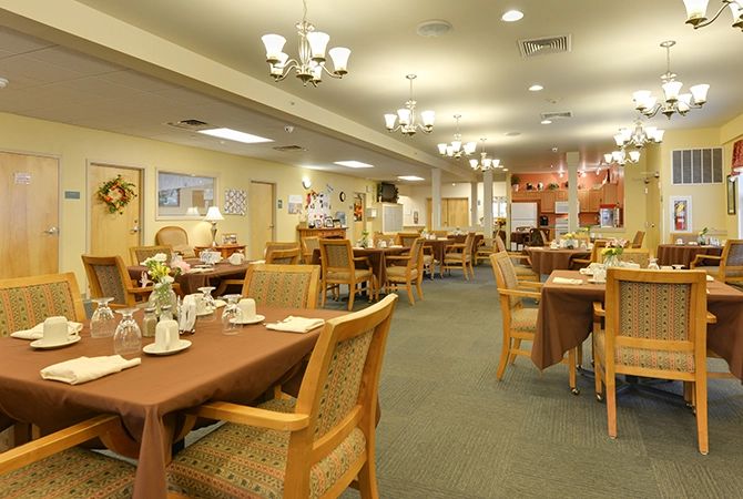 A spacious dining area with neatly arranged tables and chairs, warm lighting, and elegant interior decor.