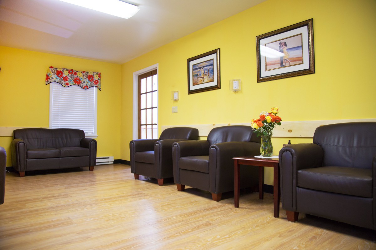 A comfortable waiting room with leather chairs, yellow walls, and decorative artwork.