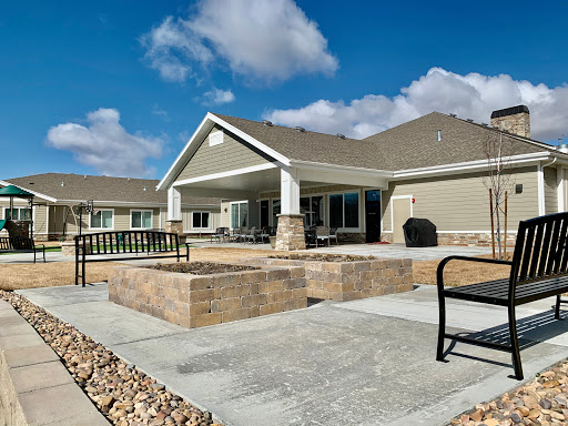 A modern house with a spacious patio area, surrounded by landscaped stone features and a clear blue sky.