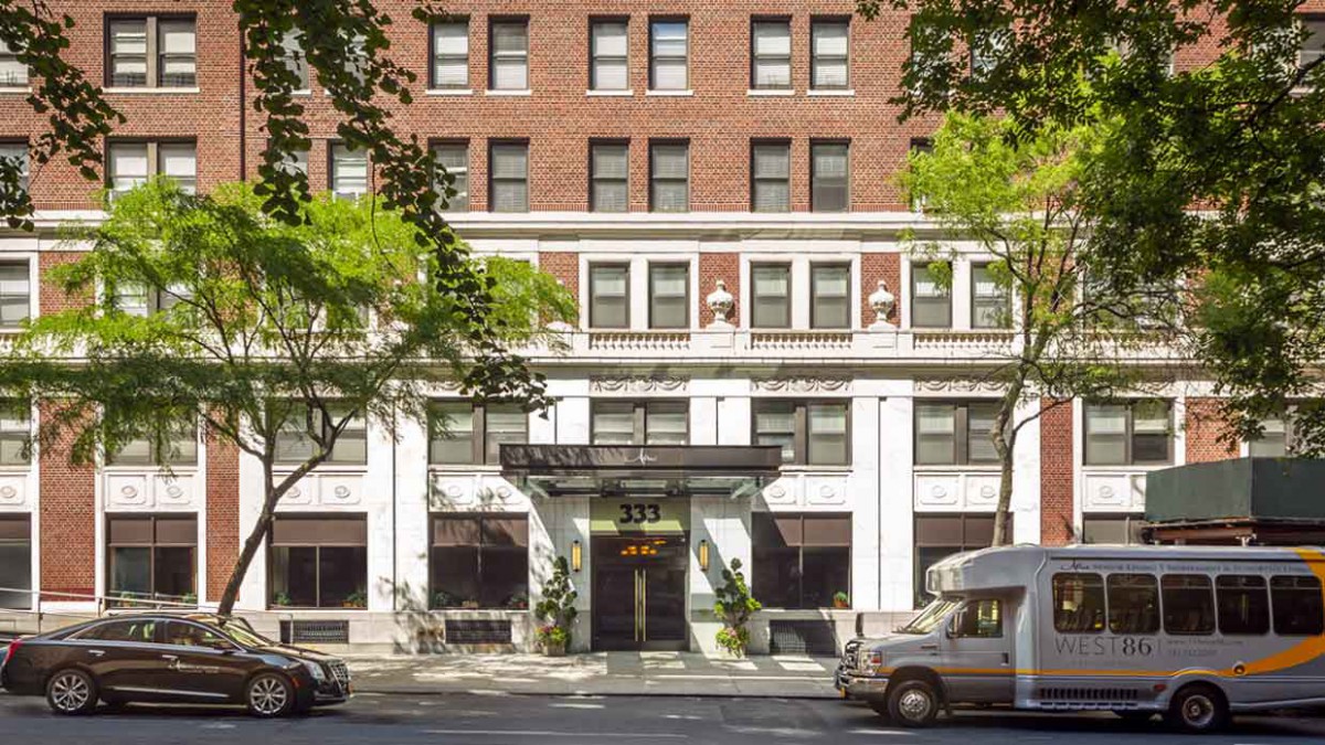 A view of a multi-story urban building with trees flanking the entrance.