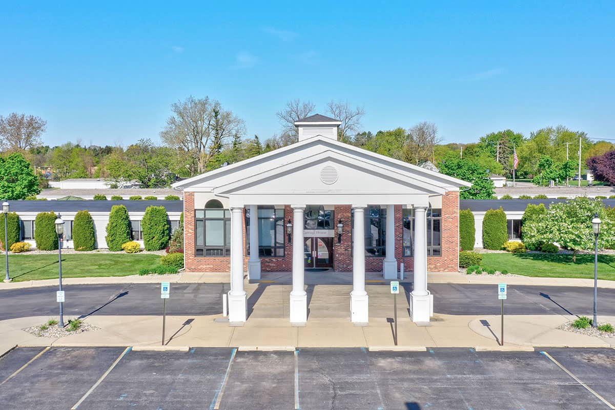 A building with a columned entrance and adjacent parking lot under a clear blue sky.