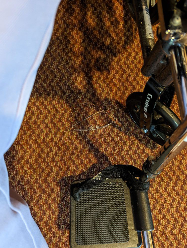 A crutch and wheelchair on a patterned carpet.