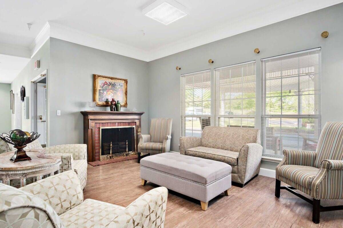 A cozy living room with a fireplace, comfortable seating, and large windows.