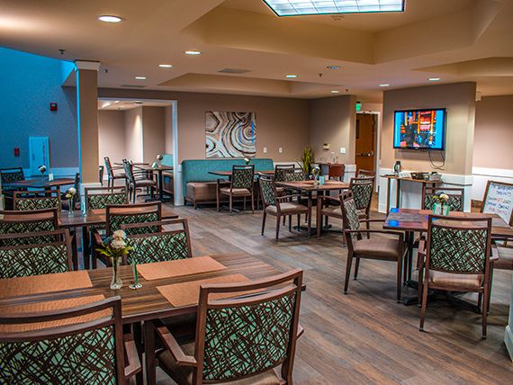 A modern and stylish restaurant dining area featuring neatly arranged tables and chairs, with elegant artwork adorning the walls.
