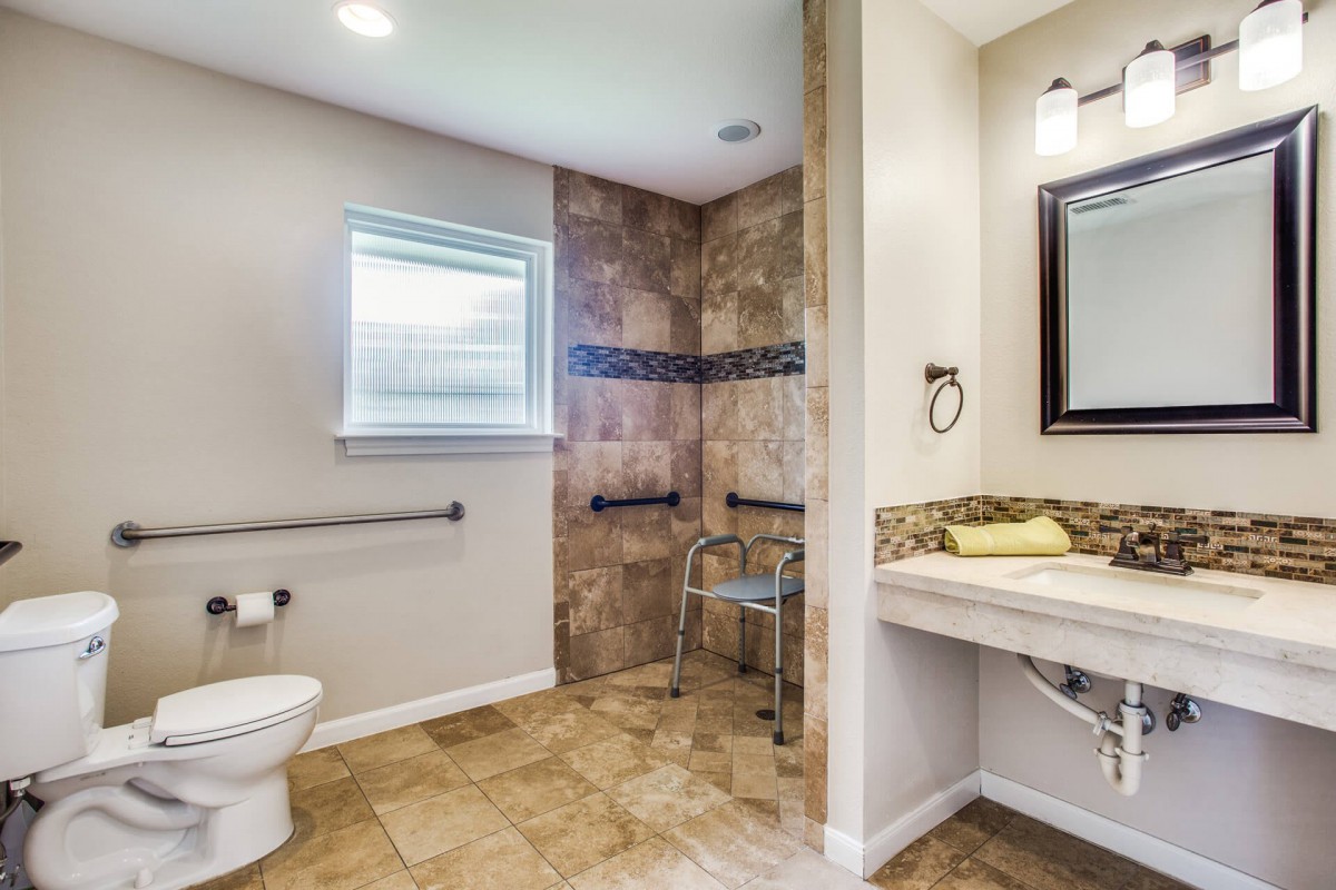 A spacious, accessible bathroom with a walk-in shower and safety features.