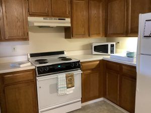 A cozy kitchen with wooden cabinets, a stove, and a microwave.