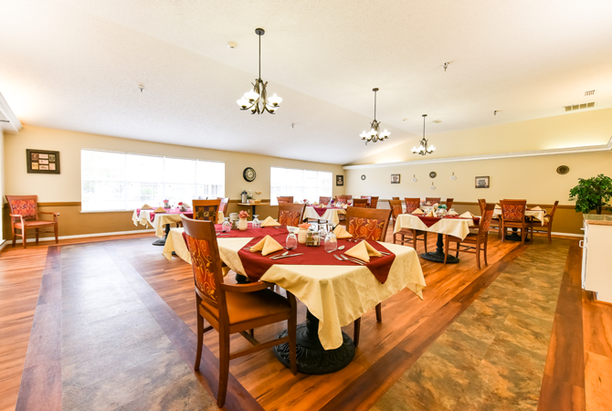 A spacious and elegantly decorated dining room with neatly arranged tables and chairs, adorned with red and white tablecloths.