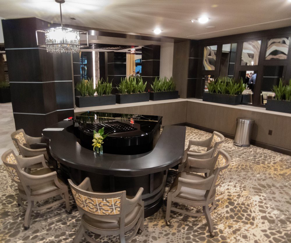 A modern dining area featuring a round table surrounded by chairs, with decorative plants and ambient lighting.