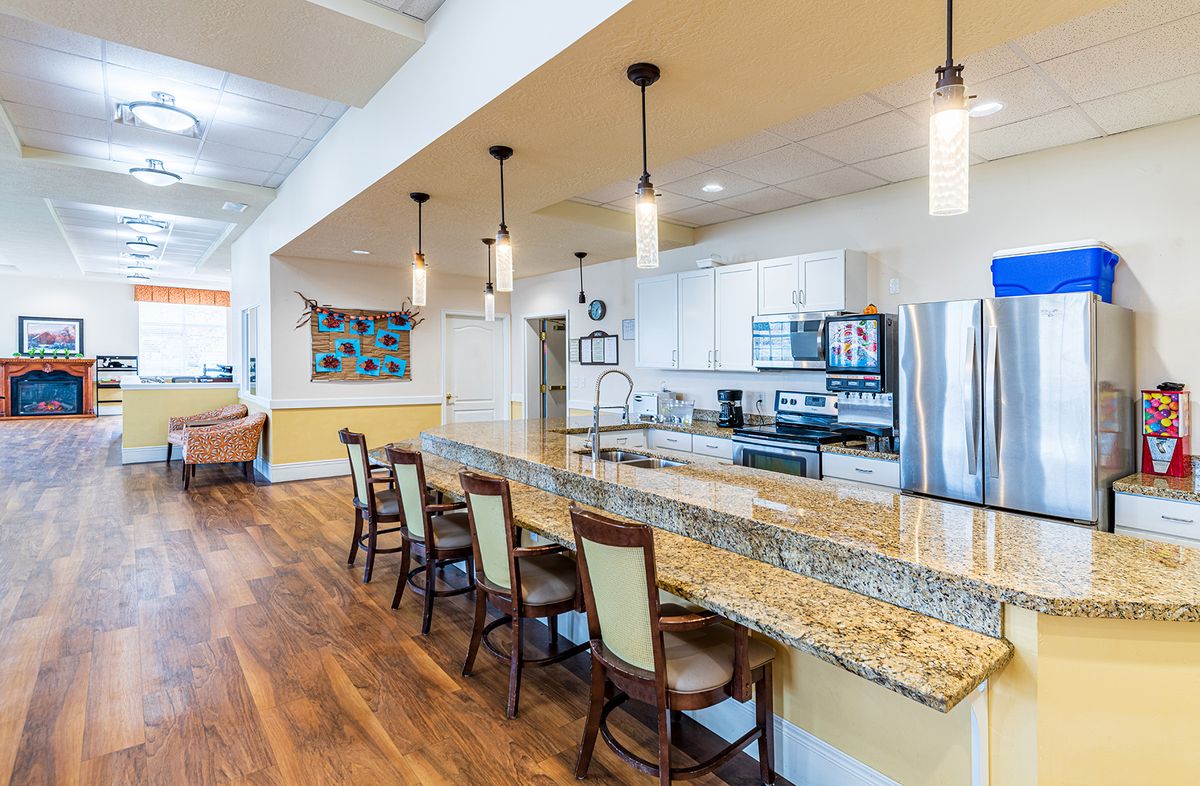 A modern kitchen with a large granite countertop and stylish pendant lighting.
