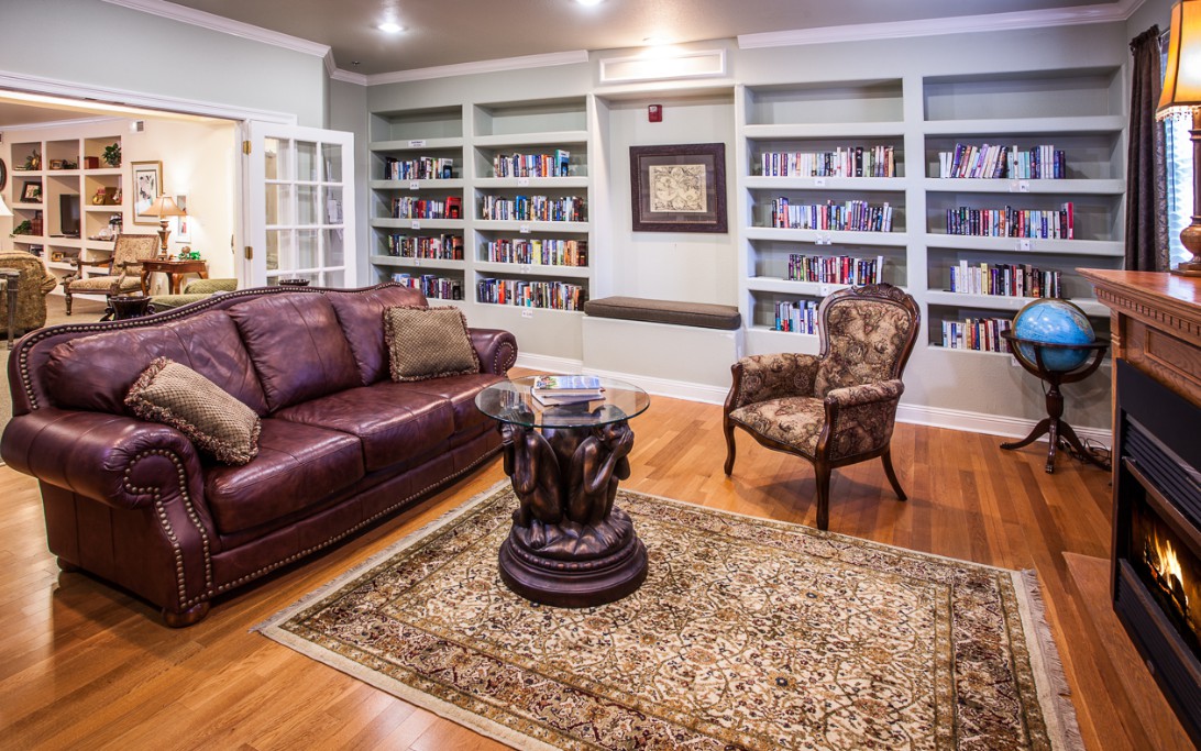 A cozy living room with built-in bookshelves, a leather sofa, and an elegant armchair.