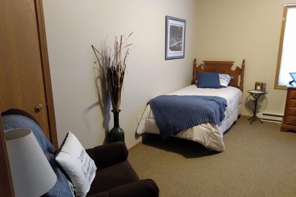 A minimalist bedroom with a single bed, decorated with a blue blanket and pillow.