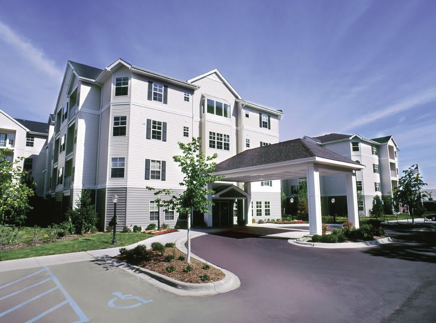 A multi-story residential building with a covered entrance and landscaped surroundings.