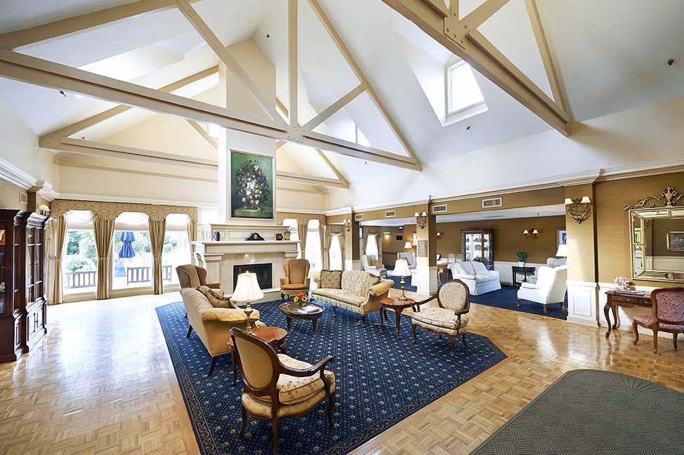 A spacious lobby with comfortable seating and a large fireplace, illuminated by natural light from skylights.