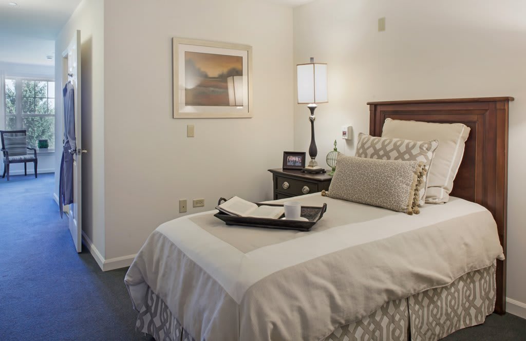 A cozy bedroom with a neatly made bed, elegant decor, and soft lighting from a bedside lamp.