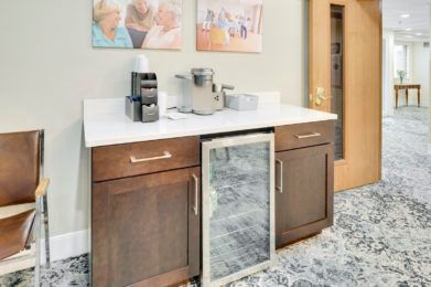 A modern coffee station with an espresso machine, coffee pods, and a beverage fridge on a countertop.