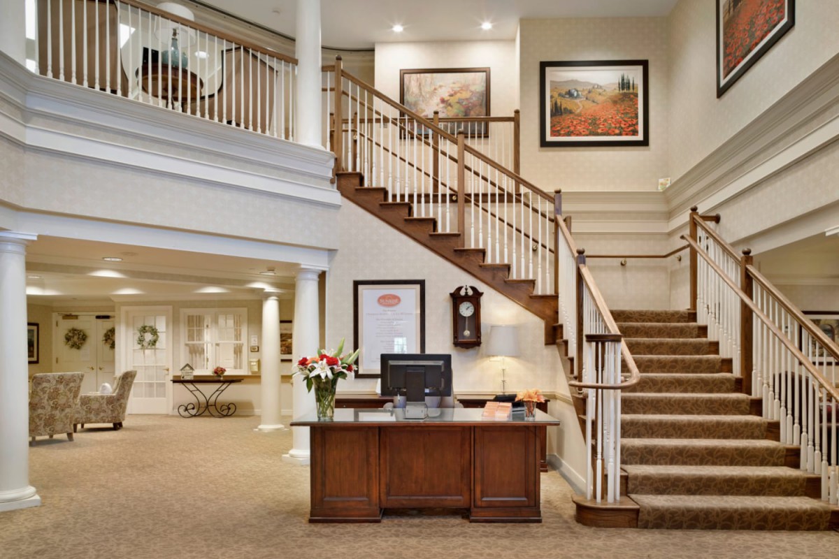A welcoming hotel lobby featuring a reception desk, staircase, and elegant decor.