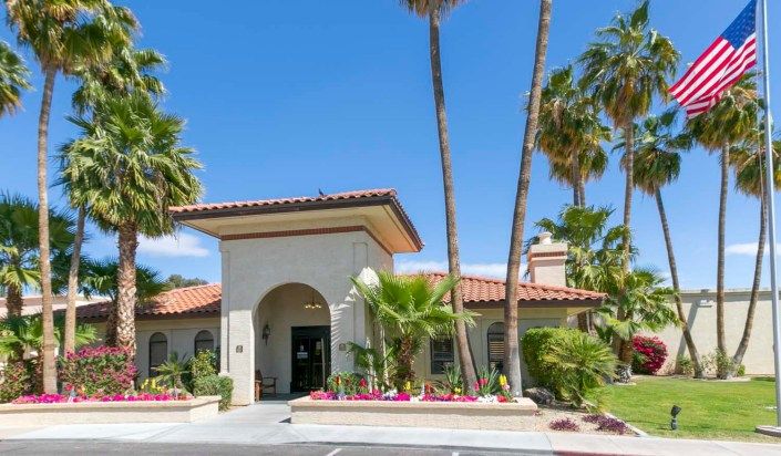 A sunny day at a building entrance surrounded by palm trees.