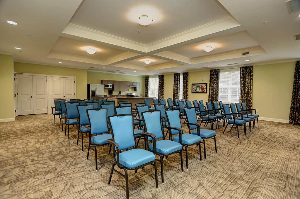 An empty conference room with rows of blue chairs arranged for a meeting.