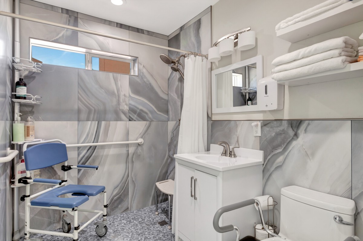 A modern, accessible bathroom equipped with a wheelchair and safety features.
