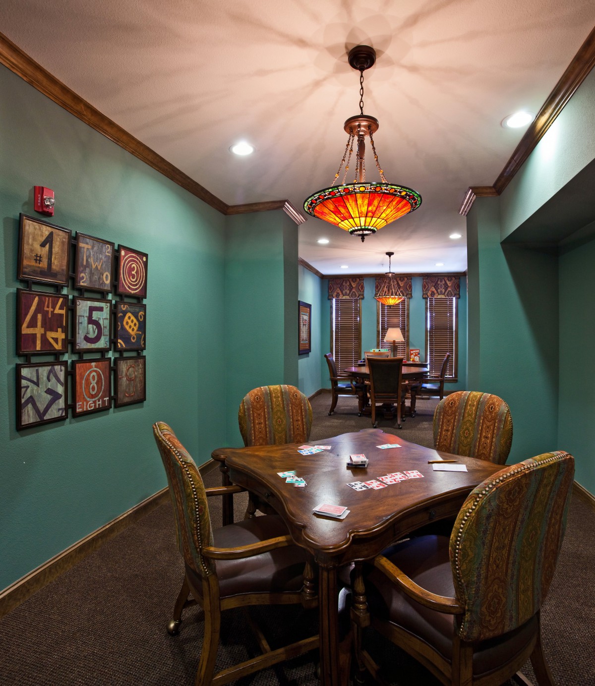 A cozy dining area with a wooden table, surrounded by chairs and decorated with unique wall art and a colorful light fixture.