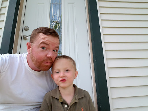 A joyful moment captured between a father and his young son outside their home.