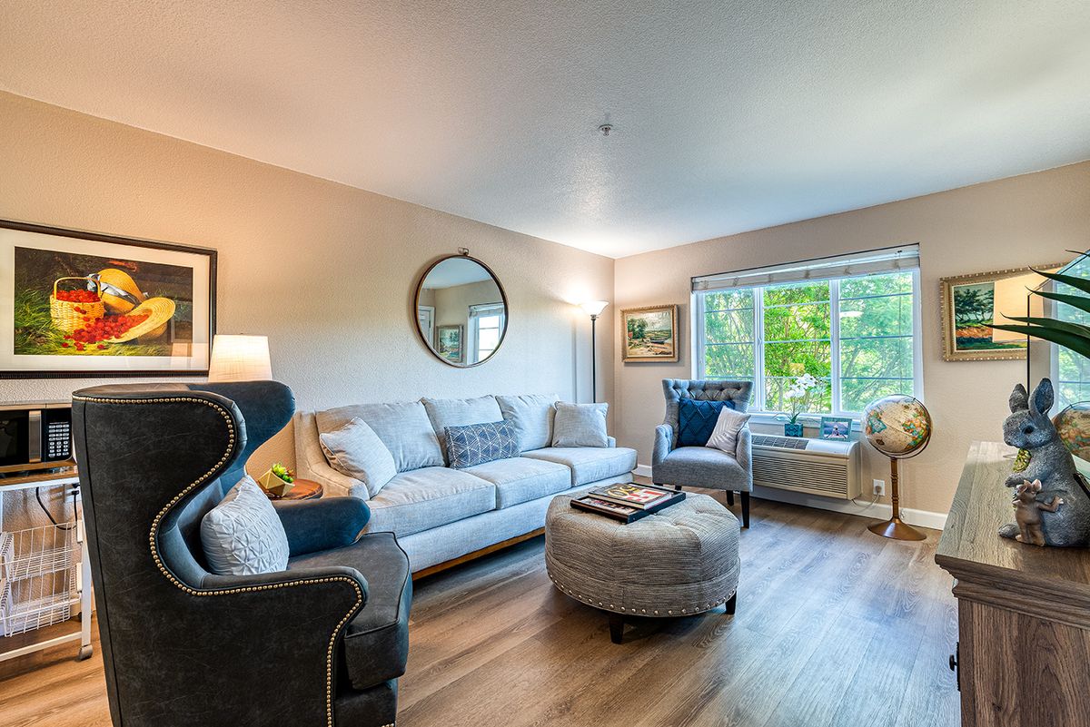 A cozy and stylish living room featuring a comfortable sofa, armchairs, an ottoman, and decorative elements like a mirror and artwork.